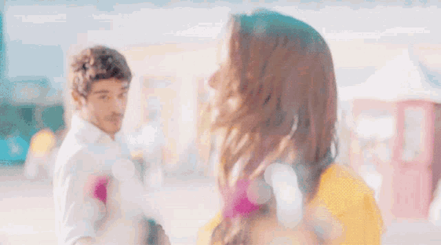 a woman in a yellow top is smiling while looking up at a man in a white shirt
