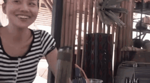 a woman in a striped shirt is sitting at a table with a pitcher of water and a straw .