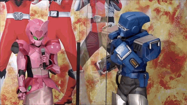 a pink robot is speaking into a microphone while a blue robot is standing behind her