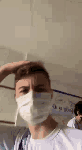 a man wearing a face mask is standing in a room .