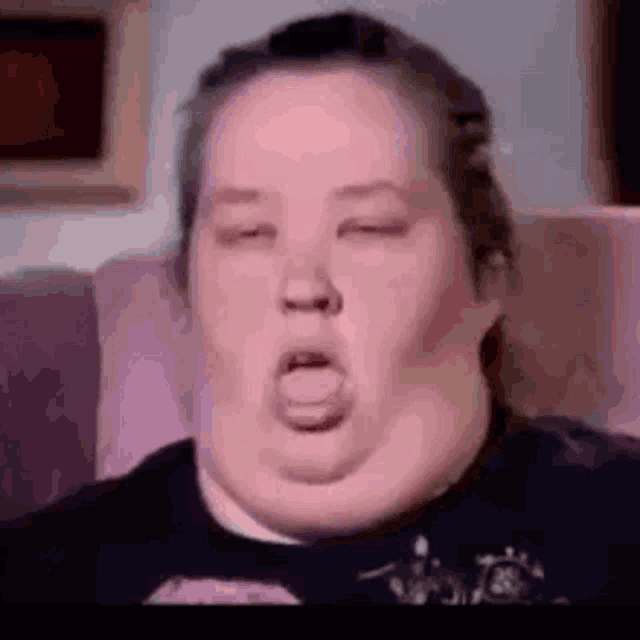 a woman is sitting on a couch with her eyes closed and her tongue out .