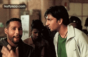 a group of men are standing next to each other in a room and talking to each other .