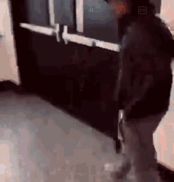 a man is walking down a hallway holding a gun in his hand .
