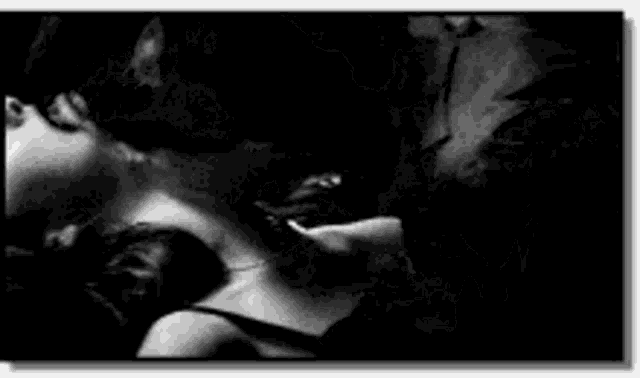a black and white photo of a woman laying on a bed with her head down .