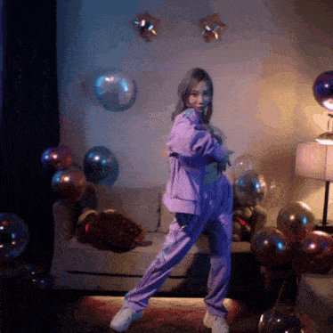 a woman in a purple outfit is dancing in front of balloons and a couch
