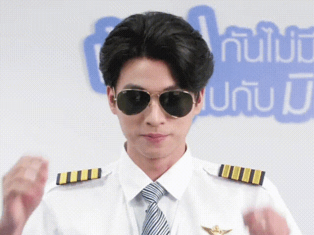 a man wearing sunglasses and a pilot 's uniform stands in front of a sign that says ' a '