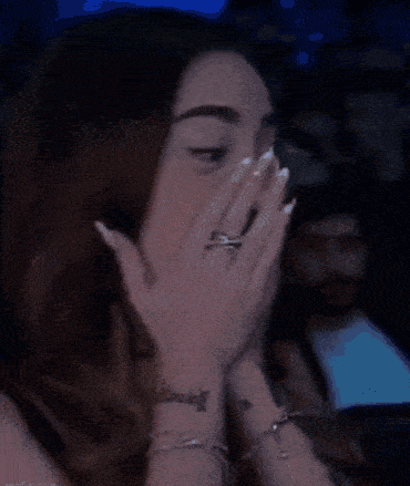 a close up of a woman covering her face with her hand