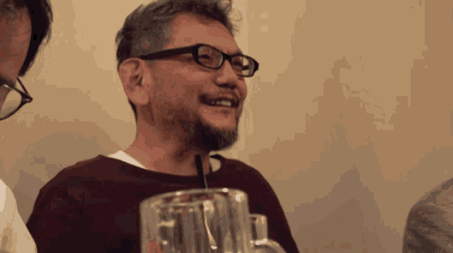 a man with glasses and a beard is holding a glass