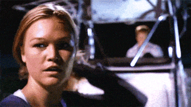a close up of a woman 's face with a man in the background behind her