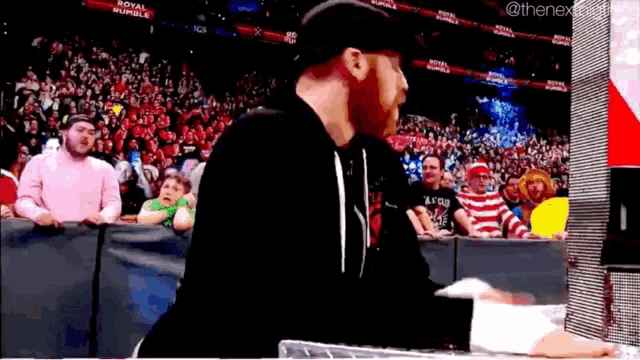 a man is standing in front of a crowd at a wrestling match .