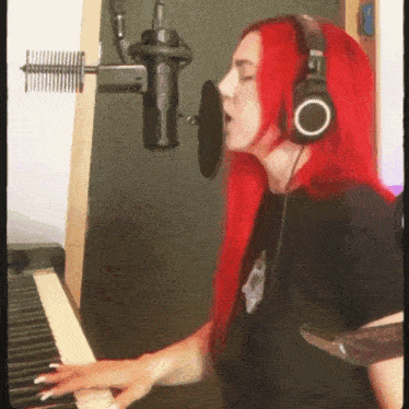 a woman with red hair is singing into a microphone while playing the piano