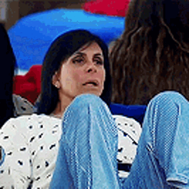 a woman is sitting in a chair with her legs crossed and talking to another woman .