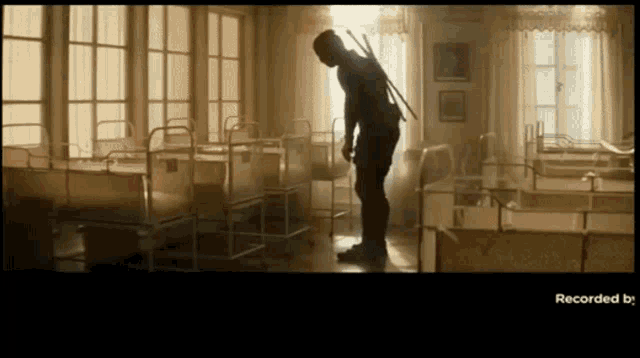 a man with a sword is standing in a room with a lot of beds