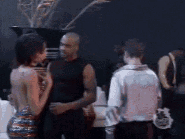 a group of people are standing in a dark room and talking to each other .