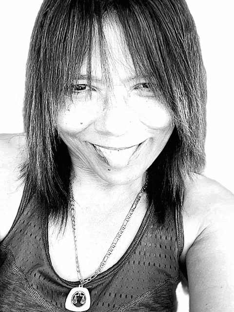 a black and white photo of a woman wearing a tank top and a necklace with a pendant that has the letter a on it