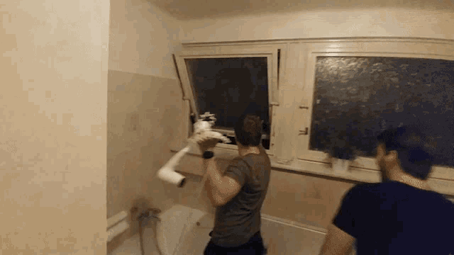 a man in a bathroom is holding a toilet paper roll