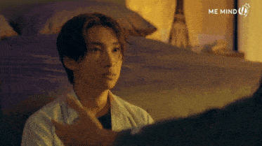 a man in a white shirt is talking to another man with me mind written on the bottom right