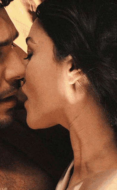 a close up of a woman kissing a man on the forehead