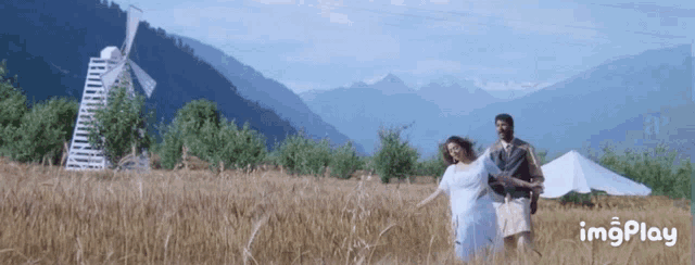 a man and a woman are dancing in a field with mountains in the background and the words imgplay below them