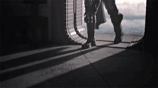 a person walking through a doorway with their shadow on the ground