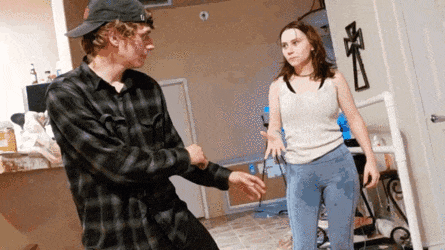 a man and a woman are standing in a room with a cross on the wall