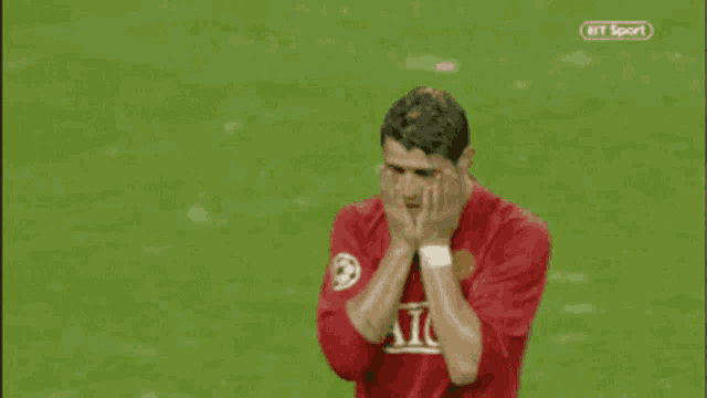 a soccer player wearing a red aig jersey is walking on the field