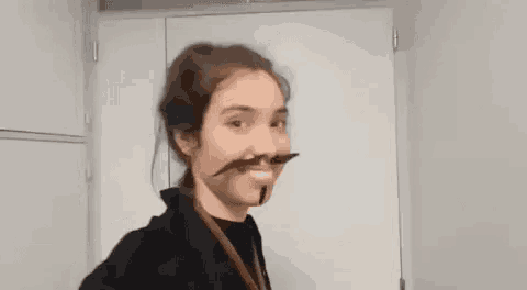 a woman with a fake mustache on her face is standing in front of a white door .