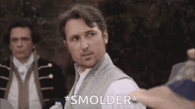 a man in a vest says " smolder " while standing in front of a group of men
