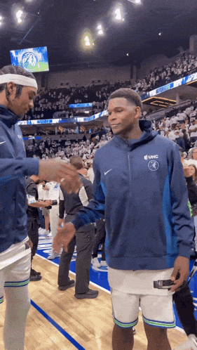 a basketball player wearing a sweatshirt that says uhc on it shakes hands with another player