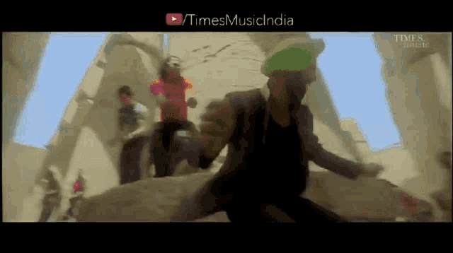 a man in a green hat is dancing in front of a group of people