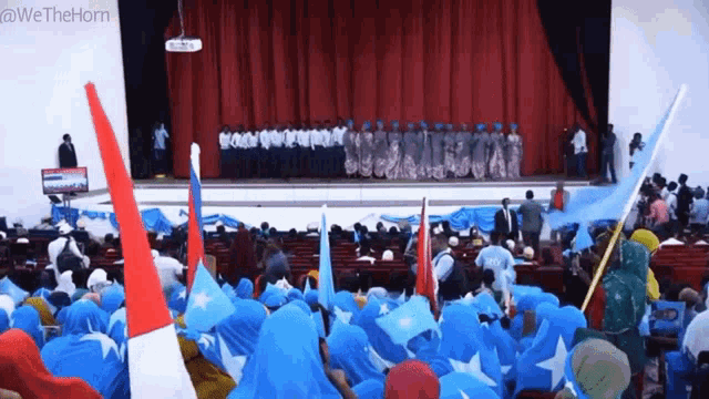 a crowd of people are gathered in front of a stage with the words we the horn written on the bottom