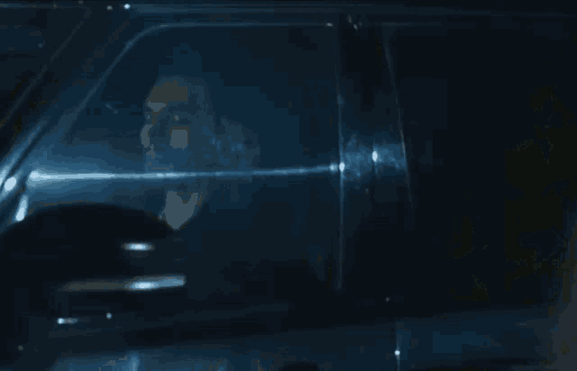 a man is driving a car at night and looking out of the window