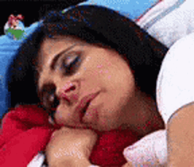 a woman is sleeping in a bed with a red blanket and a blue blanket .