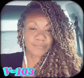 a woman with curly hair is wearing ear buds and has the letters v-103 on her face