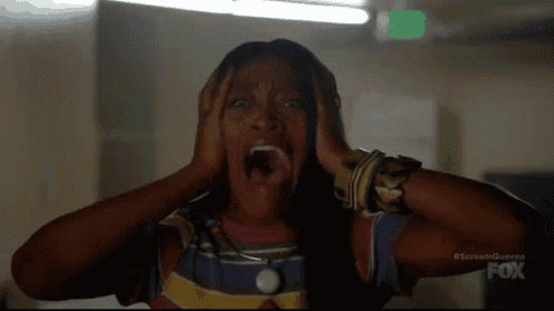 a woman is screaming with her mouth open while covering her ears with her hands .