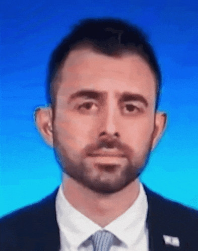a man with a beard is wearing a suit and tie with a blue background