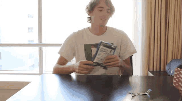 a man is sitting at a table holding a bag of chips with a nutrition facts label on it