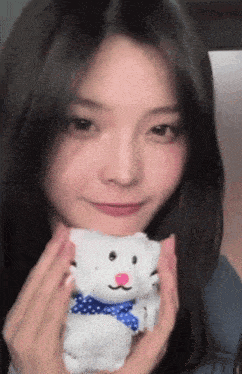 a young woman is holding a stuffed polar bear with a blue bow .