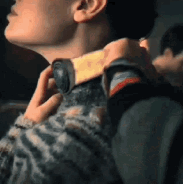 a close up of a person 's neck with a person holding their neck .