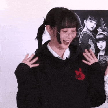 a girl wearing glasses and a black hoodie is standing in front of a painting of a girl .