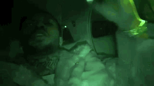 a man is laying in a bathtub with a green light shining on his face .