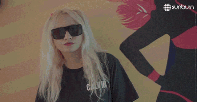 a woman wearing sunglasses stands in front of a sunburn advertisement