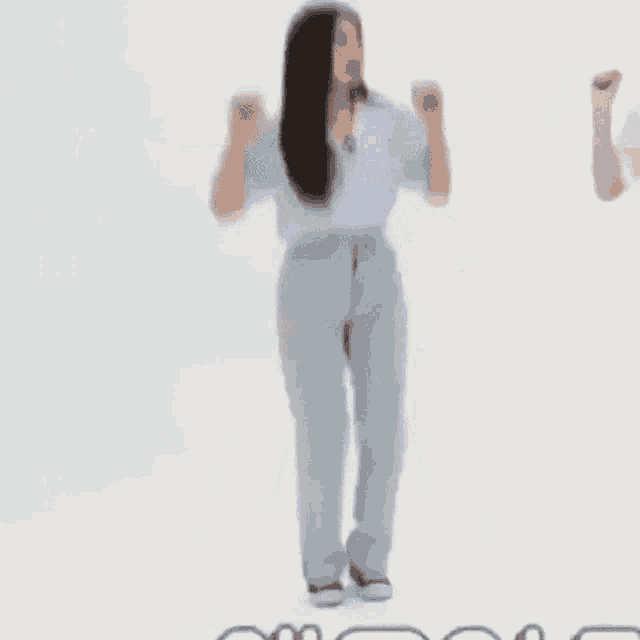 a woman is jumping in the air with her arms outstretched in a white room .