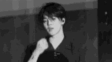 a black and white photo of a young man in a black shirt holding a microphone .