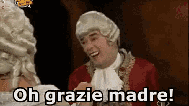 a man in a wig is talking to a woman in a wig and says oh grazie madre !