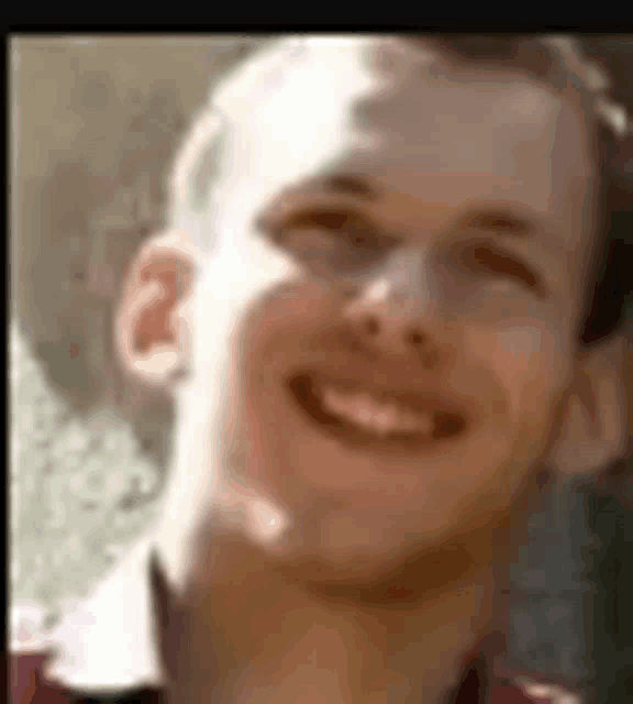 a man in a red shirt is smiling for the camera