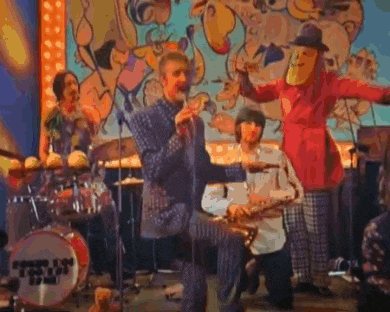 a group of people are standing on a stage playing instruments and singing into microphones .