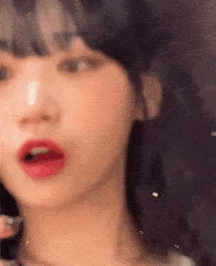 a close up of a woman 's face with her mouth open and red lips .