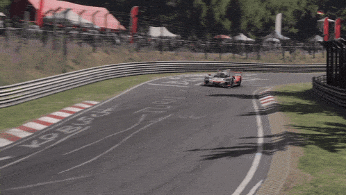 a red and white acura race car is going down a track