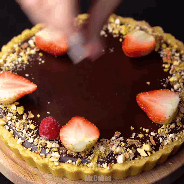a chocolate cake with strawberries and pistachios is being decorated by mr. cakes